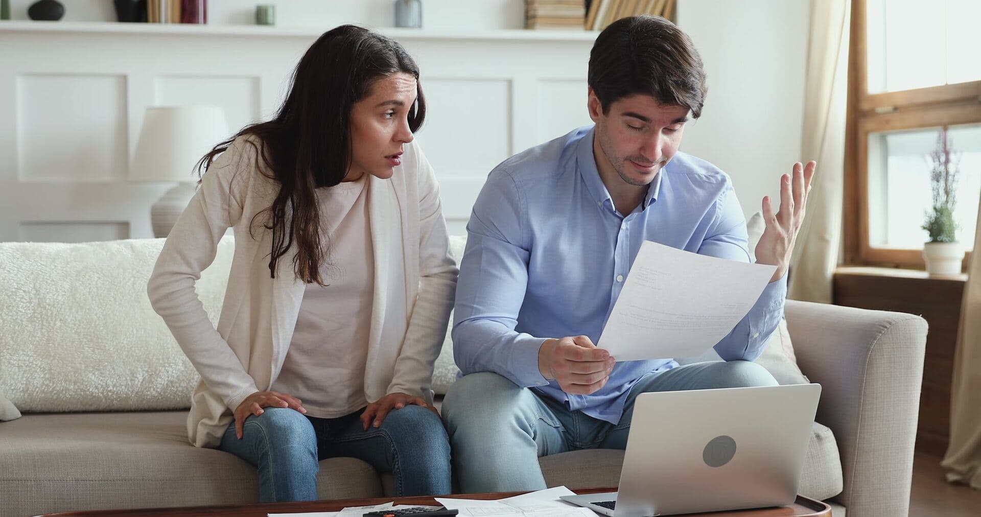 Een stel bekijkt samen gestrest een brief en rekeningen op de bank